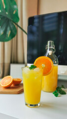 Yellow orange juice and ice on white table, refreshment drink cold beverage for hot days.