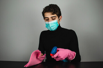 hombre joven con mascarilla guantes y desinfectante limpiando - obrazy, fototapety, plakaty