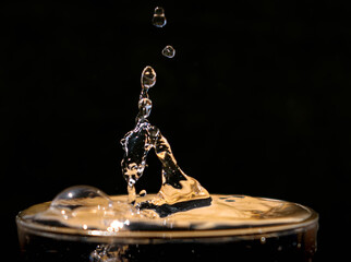 Gotas de agua cayendo sobre baso rebosante 