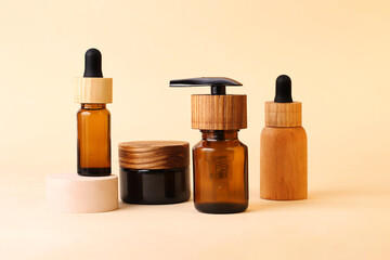 Various cosmetics containers with wooden caps on the neutral beige background.Bottle with pipette stays on the geometric podium.Zero waste,organic concept.Modern minimalism.