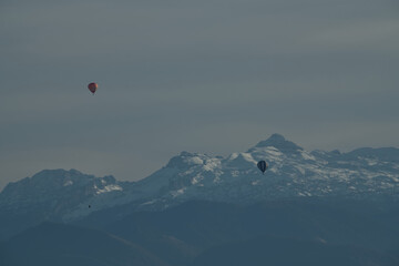 Magnifique paysage de montagne avec ses Pyrénées enneigées en toile de fond et ces deux montgolfières qui survolent la plaine des Pyrénées Atlantique par un beau jour d'automne