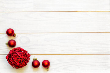A frame of red baubles on a white wooden background with copy space.