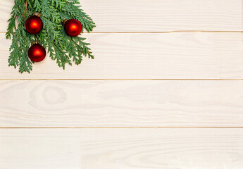 Christmas or New Year decoration background with green thuja and red baubles on a white wooden table with copy space.