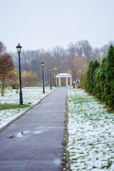 autumn park with gazebo and snow