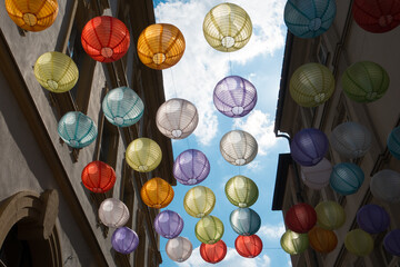  Lanterns of many colours hang in the German city of Wurzburg. Decorations are backlit against a blue sky in this street scene viewed from below