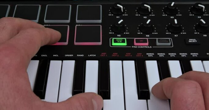 A musician plays the keyboard using a mute keyboard and the vst instruments, controls and pads