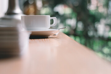 Coffee​ cup​ on the wood desk by the window with the bright light of the morning sun in the office or house,Cozy atmosphere is for relaxing on vacation,charge energy to refresh the body to working.