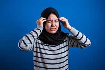 Naklejka premium Asian muslim teenage girl holding her head and close her eyes
