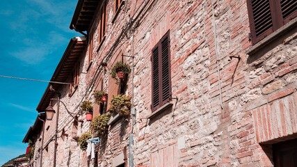 A medieval stone house in an italian village with wooden windows, plants and flowers (Gubbio, Italy, Europe)