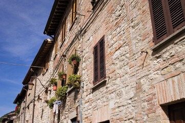 Fototapeta na wymiar A medieval stone house in an italian village with wooden windows, plants and flowers (Gubbio, Italy, Europe)