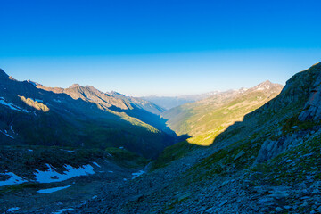 Landscape mountain view peaks in snow and green hills, deep blue sky and huge white clouds background, Hohe Tauern Austrian Alps, Europe