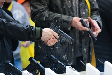 Obraz premium Vicenza, Italy - February 8, 2020: a man inspects a 9mm Walther Arms handgun on display during Hit Show 2020, trade fair show dedicated to hunting, target sports and outdoor in Vicenza, Italy