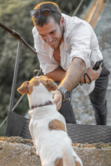 Portrait of smiling young man and small cute purebred dog jack russell terrier together outside