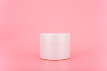 White glossy cream jar on a pink background. Minimalistic concept of beauty and skin care