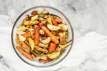 Baked vegetables on concrete background. Potatoes, carrot, mushrooms and onions.
