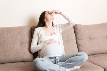 Obraz premium Sick pregnant woman blowing nose into tissue at home Healthy millennial healthcare concept