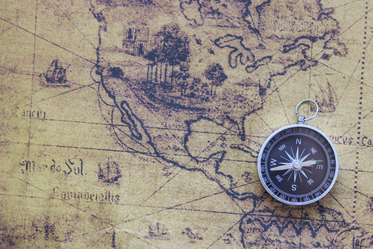 Classic round compass on old vintage map depicting North America and the United States of America as symbol of tourism with compass, travel with compass and outdoor activities with compass