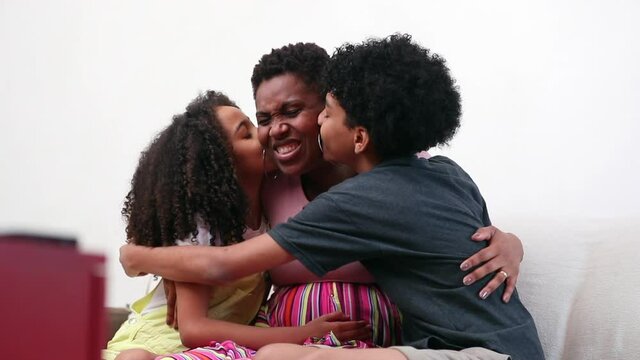 Children kissing mother in cheek, mix race little brother and sister hug black mom