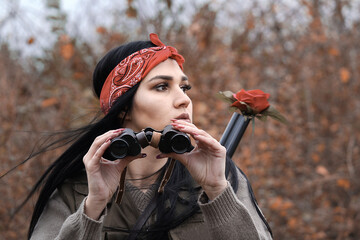 A beautiful girl hunter holding binoculars