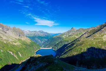 Naklejka na ściany i meble Morning mountain dawn in the Alps surrounded by summer green in the background high Alps, cloud sky. Reflections mountains in the water Zillergrundl austria zillertaler alps