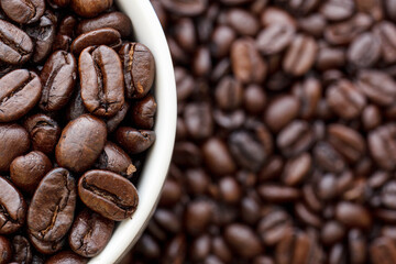 Roasted coffee beans in a cup on left side of frame.