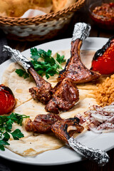 Rack of lamb or turkish pirzola kuzu with bulgur, grilled vegetables and spices on a white plate....