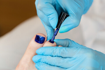 Process pedicure close up. Unrecognizable people. Master chiropody applying gel nail polish. Spa....