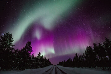 Northern lights Aurora Borealis activity over the road in winter Finland