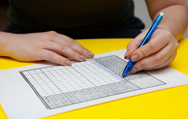 The woman solves the Japanese crossword puzzle with her left hand. Lefty