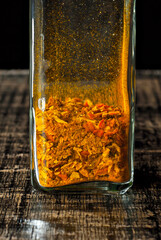 A mixture of various spices in a glass jar close up. Spices and condiments on a black, old shabby board. Free space and copy space for text near condiments.