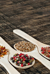 A mixture of various spices in a wooden spoon. Spices and seasonings on an old shabby board. Mix on a pile close up. Place for text and copy space near the spoon.