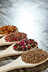 A mixture of various spices in a wooden spoon. Spices and seasonings on an old shabby board. Mix on a pile close up. Place for text and copy space near the spoon.