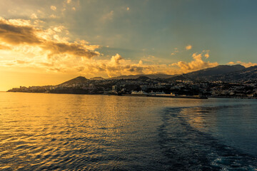 A golden sunset over the city of Funchal, Madeira viewed from a ship sailing away from the island