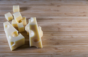The cheese is on a wooden board. Cut into small pieces