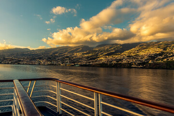 Sailing past the coast of  Funchal, Madeira with the city bathed in the glow of the setting sun