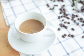 Coffee in a black coffee cup Placed on a fabric with coffee beans and morning alarm clocks.
