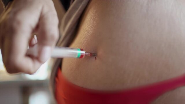 A mature woman gives herself an injection with Vitamin B, a woman sits at home with Covid-19 and gives herself a close-up syringe injections.The woman makes an injection into the intramuscularly.