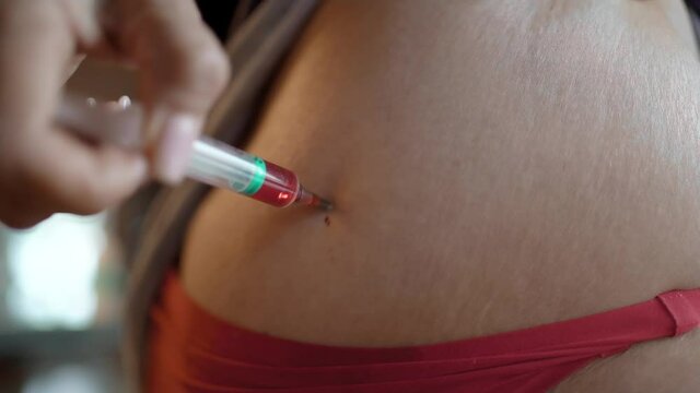 A mature woman gives herself an injection with Vitamin B, a woman sits at home with Covid-19 and gives herself a close-up syringe injections.The woman makes an injection into the intramuscularly.