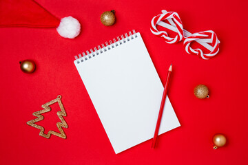 Top view mockup image of white blank notebook with christmas decorations on red background. Flat lay style. Planning concept.
