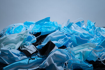 Medical masks on the table. Pile of used personal protective equipment PPE. Pollution by surgical masks during the coronavirus pandemic. A lot of Covid-19 plastic waste and garbage, disposable masks.