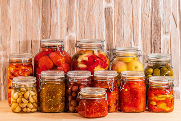 Fototapeta na wymiar Canned vegetables, fruits and berries with spices, in beautiful glass jars. On a wooden table.