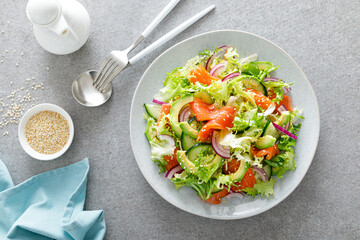 Salmon avocado salad with salted fish, fresh lettuce and red onion