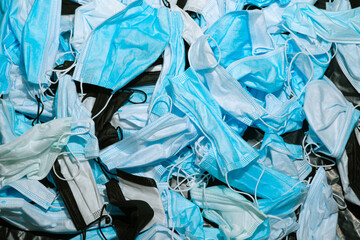 Medical masks on the table. Pile of used personal protective equipment PPE. Pollution by surgical masks during the coronavirus pandemic. A lot of Covid-19 plastic waste and garbage, disposable masks.