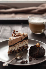 Plate with slice of tasty chocolate cake and cup of cappuccino on table