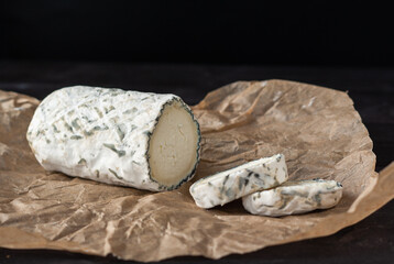 Delicious goat chevre cheese slices on a dark wooden background.