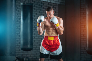 strong sportsman boxer exercising in white gloves at gym