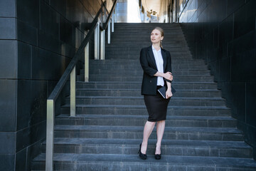 Business woman in on the steps with a notebook in her hand