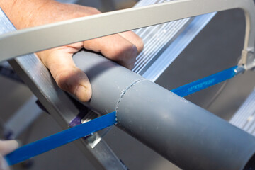 Plumber saws a water pipe with a jigsaw for draining, repair in a new apartment