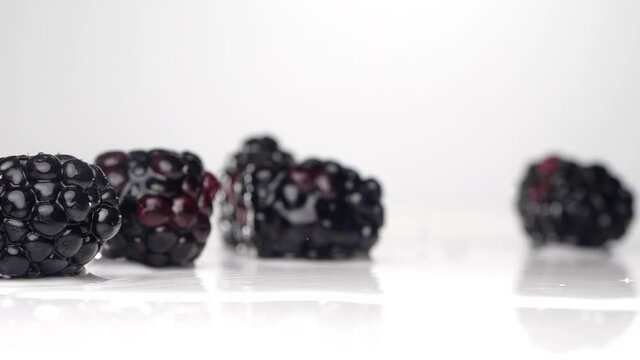 Juicy blackberries fall on the table. Сlose up slow motion.