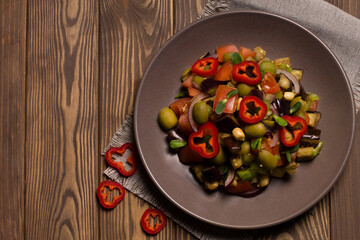 Traditional Sicilian dish of eggplant caponata on a wooden table. Top view